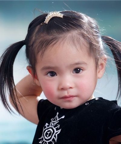 可爱的圆脸女孩梳理着中短发,妈妈将小女孩的齐刘海中短发在耳后后