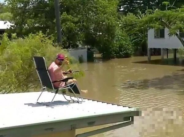 洪水袭击澳大利亚昆士兰 男子淡定在房顶喝酒钓鱼